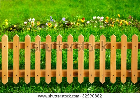 Wooden garden fence against green grass and flowers