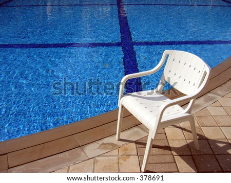 A White Chair by the side of a Swimming Pool