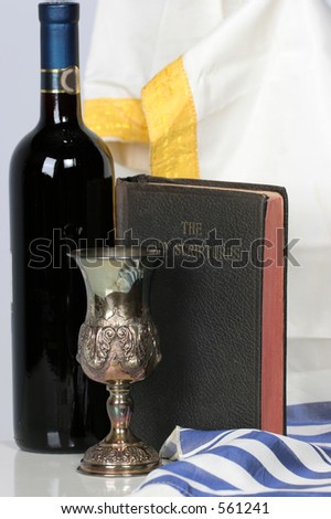 Holy Scriptures standing with Talid behind it a Kaddish cup and a bottle of red wine