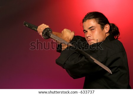 black belt holds katana a single edged  Japanese sword in warm red light