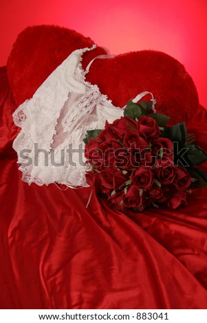 white teddy with red roses on satin sheets