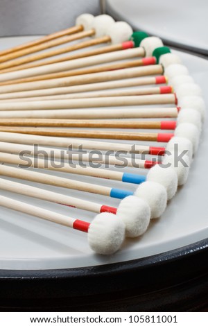 Marimba mallets with white heads resting in a quarter circle