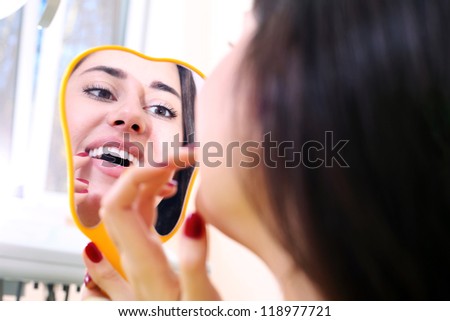 Pretty girl examines her teeth in the mirror