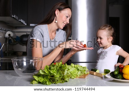 mother helping her daughter prepare salad in the kitchen