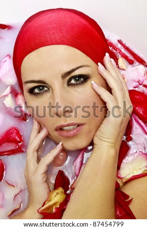 woman beauty  with red flower petals in bath with milk
