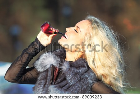 Young girl smokes a pipe on the nature