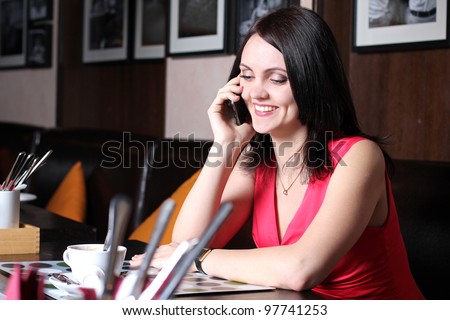 Young girl sitting in a cafe for a cup of tea and talking on the phone
