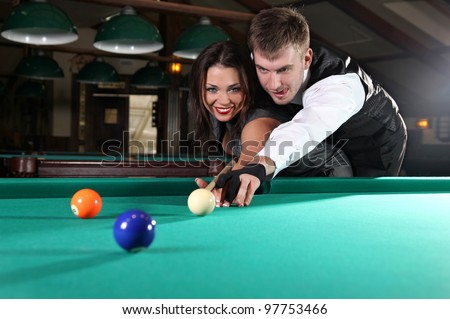 Portrait of a couple playing snooker in a dark club