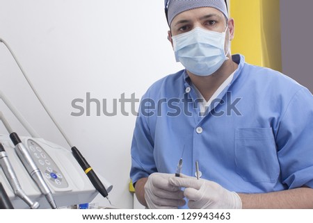Dentist male preparing a syringe to anesthetize his patient. Focus on syringe.