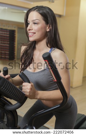 Beautiful woman working out in a health club on elliptical trainer.