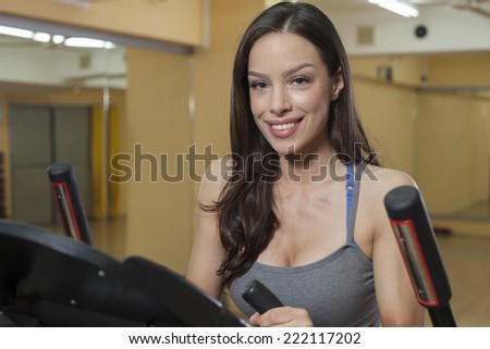 Beautiful woman working out in a health club on elliptical trainer.