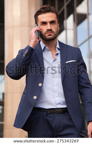 Businessman talking on the phone walking on the street