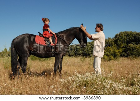 a father training his daughter for horseback riding