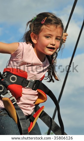 Little girl jumping on the trampoline (bungee jumping).