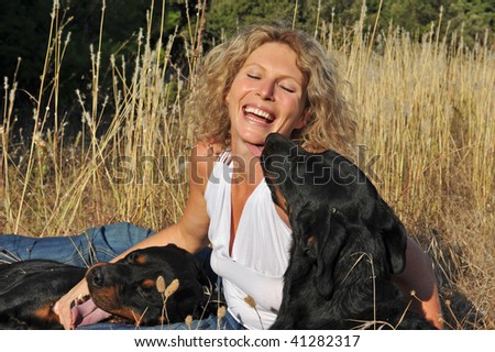 laughing young woman and her two dogs: rottweiler and french shepherd