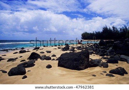 Lava rocks lie on the sand at Ke\'e Beach on the north shore of Kauai, Hawaii.