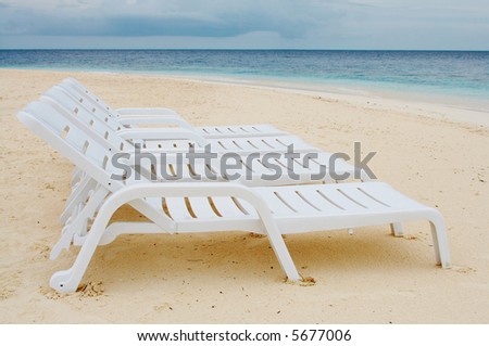 Four chaise-longue on the beach of Ocean. White Sand and Crystal blue water.