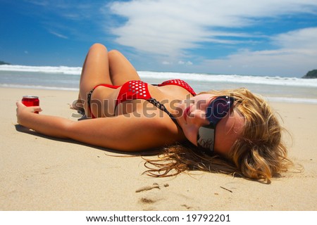 stock photo Young girl in red bikini is lying on white sand beach
