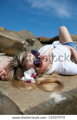 Cute summer style girl is lying on stones