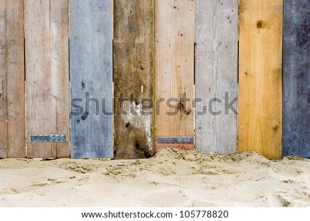 A fence on a beach made from wood which used to be part of a scaffold