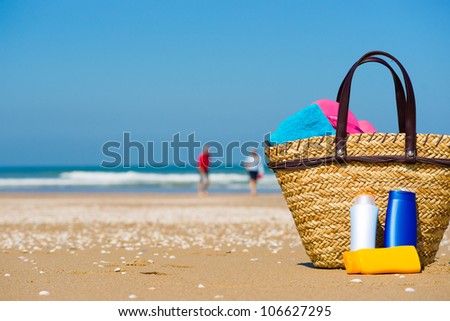 Bottles of sun screen in a basket. A happy older couple in the blurred background