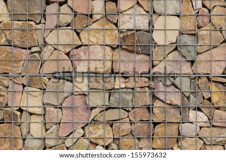 various stones carefully aranged in an iron net to make  a wall