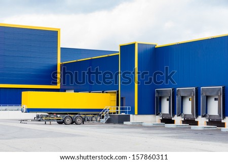 warehouse painted yellow and blue with a trailer in front
