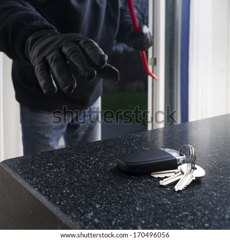 Mean looking burglar enters a kitchen to grab the car key from the kitchen counter