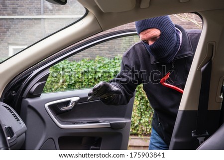 A burglar in action to rob something out of a car