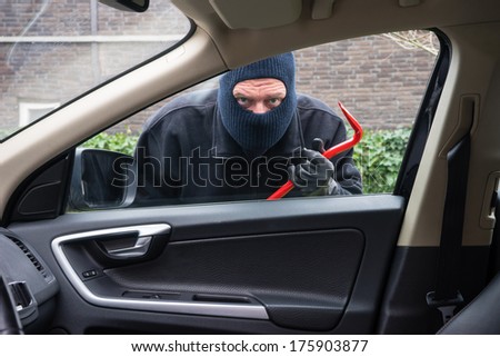 A burglar in action to rob something out of a car
