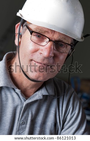 portrait of a happy engineer with safety helmet, earplugs and safety glasses
