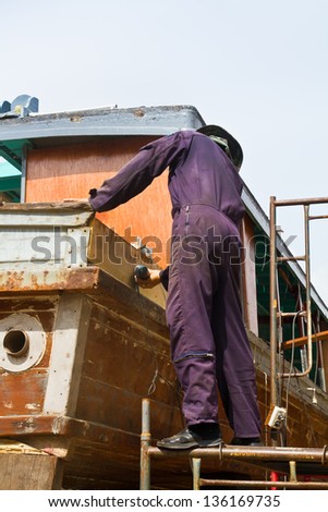 Carpenter is repairing boat in dry dock
