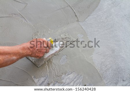 Hand using trowel on fresh concrete in construction site