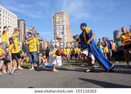 KIEV, UKRAINE - JUNE 11: Swedish football fans dance with a elderly ukrainian woman during Euro-2012 on June 11, 2012 in Kiev, Ukraine. The Ukrainian host cities are Lviv, Donetsk, Kharkiv and Kiev.