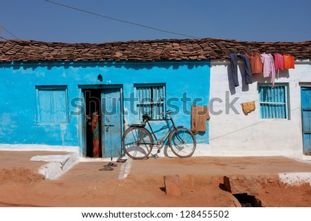 ORCHHA, INDIA - DEC 23: Traditional indian house of blue color with a woman standing in the doorway on December 23 2012 in Orchha, India. Town Orchha in Madhya Pradesh state has a population of 10000