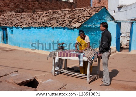 ORCHHA, INDIA - DEC 20: Indian woman irons clothes coal iron outdoor at the bright day on December 20 2012 in Orchha, Madhya Pradesh, India. Orchha had a population of 10000. Females constitute 47%