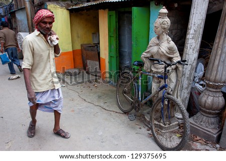 KOLKATA, INDIA - JANUARY 21: Hindu man walks past a bicycle parked at a ancient woman sculpture on January 14, 2013 in Kolkata, India. Kolkata has a density of 814.80 vehicles per km road length.