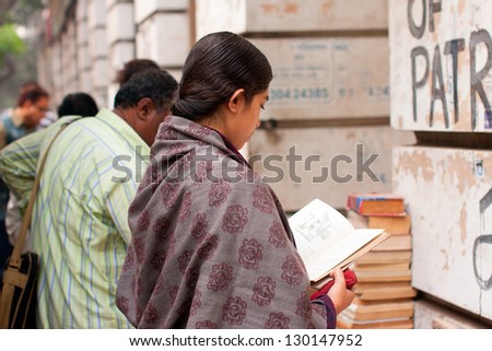 KOLKATA, INDIA - JANUARY 18: Asian woman read the book near the street book stall on January 18, 2012 in Kolkata, India. From 1976 Kolkata have the biggest Book Fair with 2 million people every year.