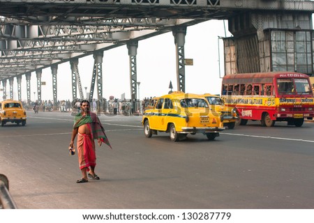 KOLKATA, INDIA - JAN 13: Poor man goes busy road in the wrong place on the Howrah bridge on January 13, 2013 in Kolkata. Howra bridge bears 100,000 vehicles and more than 150,000 pedestrians every day
