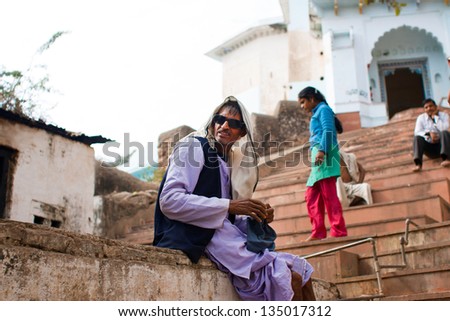 CHITRAKOOT, INDIA - DEC 29: Elderly asian man sits on the steps outdoor on December 29, 2012 in Chitrakoot, India. Population of Chitrakoot is 22,294. By the legend, god Rama lived here 11 years