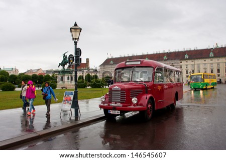 VIENNA, AUSTRIA - JUNE 4: People walking on rainy street past the antique touristic bus on June 4, 2013 in Vienna, Austria. Vienna attracts about five million tourists a year.