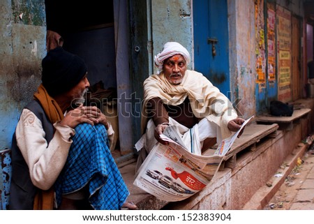 VARANASI, INDIA - JAN 1: Two aged men discuss the latest news and read the morning newspaper outdoor on January 1, 2013 in Varanasi, India. The literacy rate in the Varanasi urban agglomeration is 77%