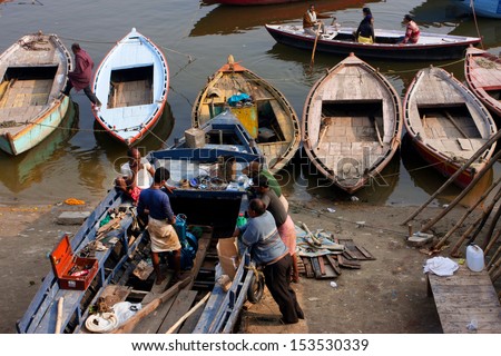 VARANASI, INDIA - JANUARY 2: Meeting the Indian men who try to fix the motor of an old riverboat at the Ganges river dock on January 2, 2013. Varanasi urban agglomeration has a population of 1,435,113