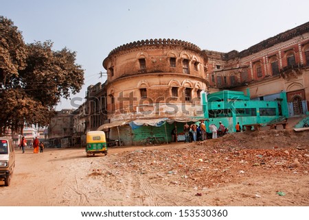 VARANASI, INDIA - JANUARY 3: Old yellow auto rickshaw drive past the walls of Ramnagar Fort on January 3, 2013. The Ramnagar Fort of Varanasi was built in 1750 in typical Mughal style of architecture