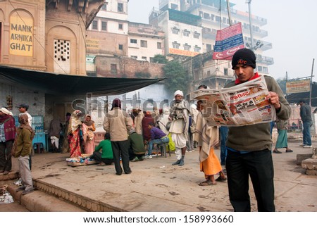 Varanasi, India - January 4: Young Man Reads A Newspaper In The Crowd Of Hindu People At The Morning On January 4 2013. The 2,525 Km River Rises In Indian State Uttarakhand &Amp; Flows Into Bangladesh