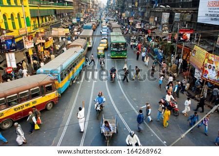 CALCUTTA, INDIA - JAN 18: Pedestrians cross the road in front of motorcycles, cars and buses at the crossroads on January 18, 2013 in India. Kolkata has a density of 814.80 vehicles per km road length
