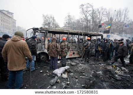 KYIV, UKRAINE - JAN 21: Many men in uniform and helmets overturned burned bus on the occupying street during anti-government protest Euromaidan on January 21, 2014, in center of Kiev, Ukraine.