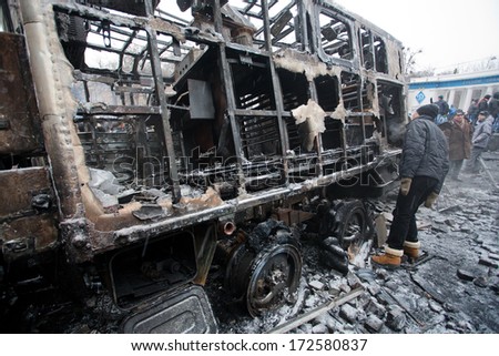 KYIV, UKRAINE - JAN 21: Young men look at the burned out military auto on the barricades of occupying snow city during anti-government protest Euromaidan on January 21, 2014, in Kiev, Ukraine