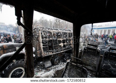 KYIV, UKRAINE - JAN 21: Burned out buses and military auto stand in the occupying street with crowd of protesters during anti-government protest Euromaidan on January 21, 2014, in Kiev, Ukraine