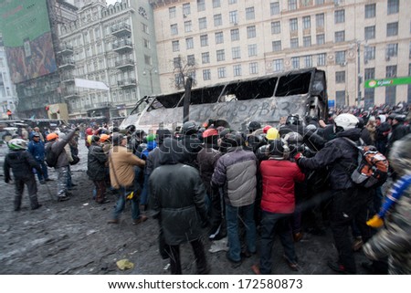 KYIV, UKRAINE - JAN 21: Angry crowd on the occupying street overturned burned-out bus on the demostration during anti-government protest Euromaidan on January 21, 2014, in center of Kiev, Ukraine.